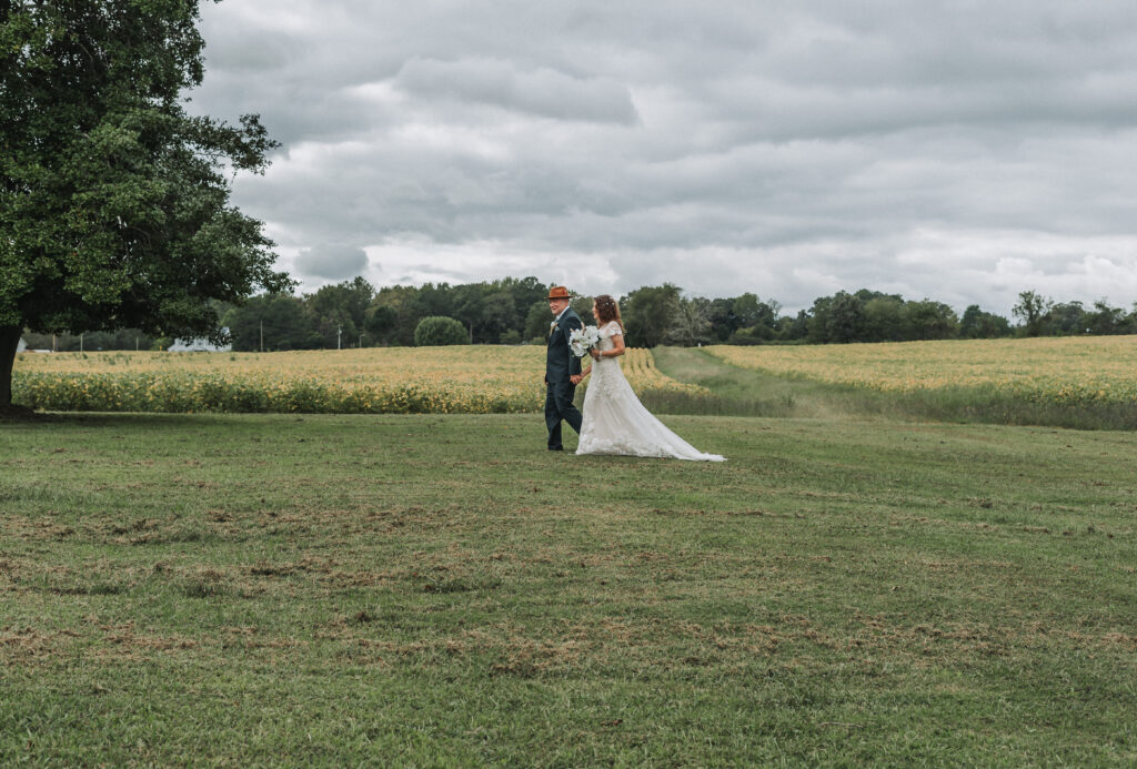 A bride and groom walking hand in hand at their wedding at the Walnut Valley House in Chippokes Virginia shot by Quinn Photography LLC.