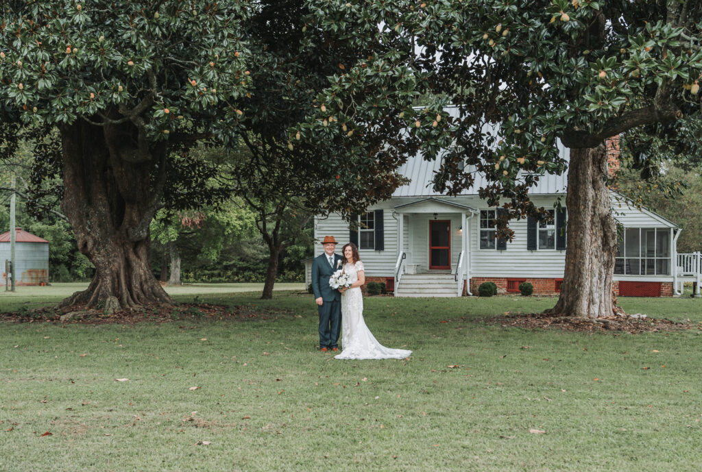 A bride and groom standing under the magnolia trees symbolizing their love for each other. Wedding at Walnut Valley House in Chippokes Virginia, shot by Quinn Photography LLC.