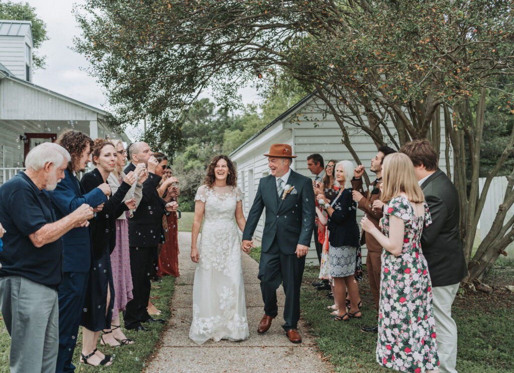 Bride and groom walking through their bubble exit, smiling, hand in hand at the Walnut Valley House in Chippokes. Shot by Quinn Photography LLC