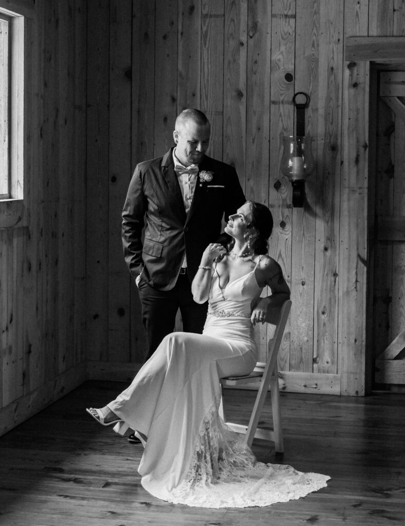 Groom stand at an angle from his bride to be, and rests his hand on her shoulder. Bride is looking up at the groom and holding his resting hand on her shoulder. Gentry Farm Wedding Venue, Danville Virginia- Quinn Photography LLC