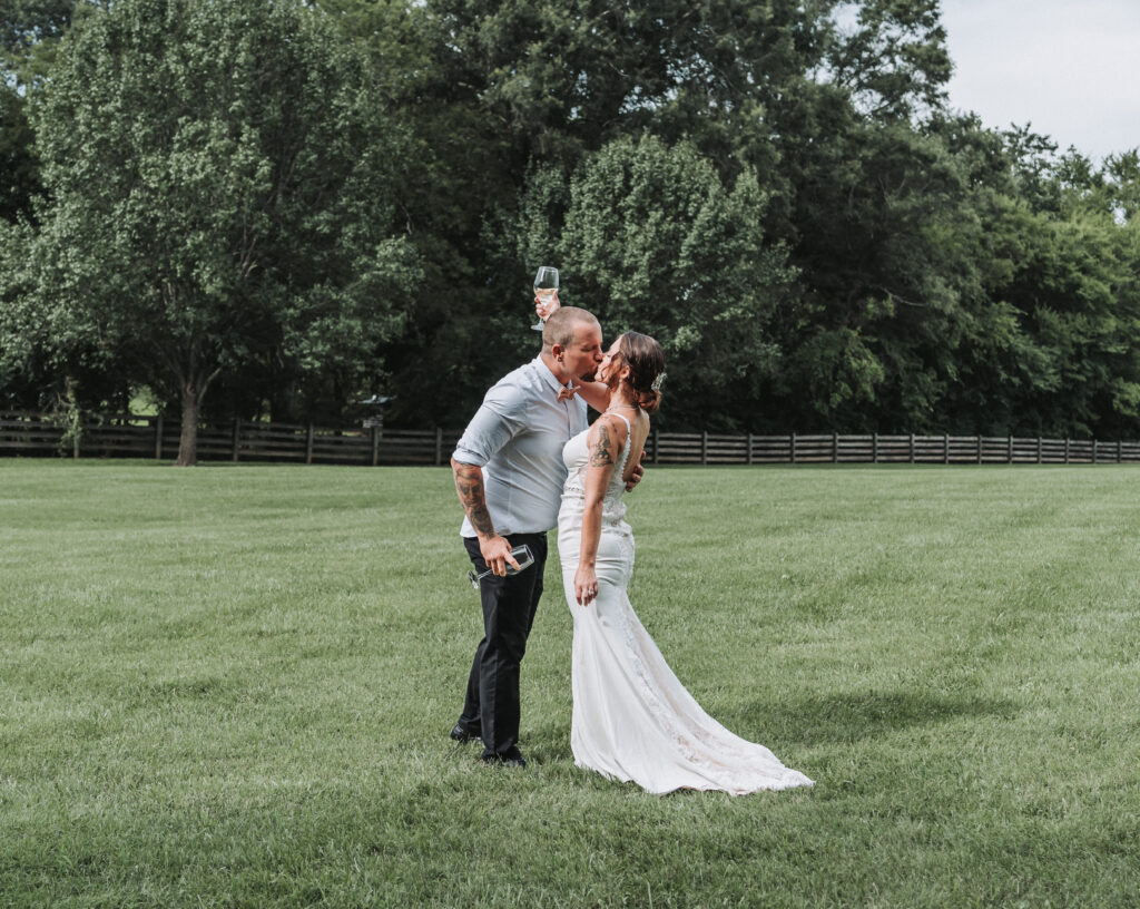 Bride and groom sharing a romantic kiss whilst enjoying their champagne for a photo- Quinn Photography LLC