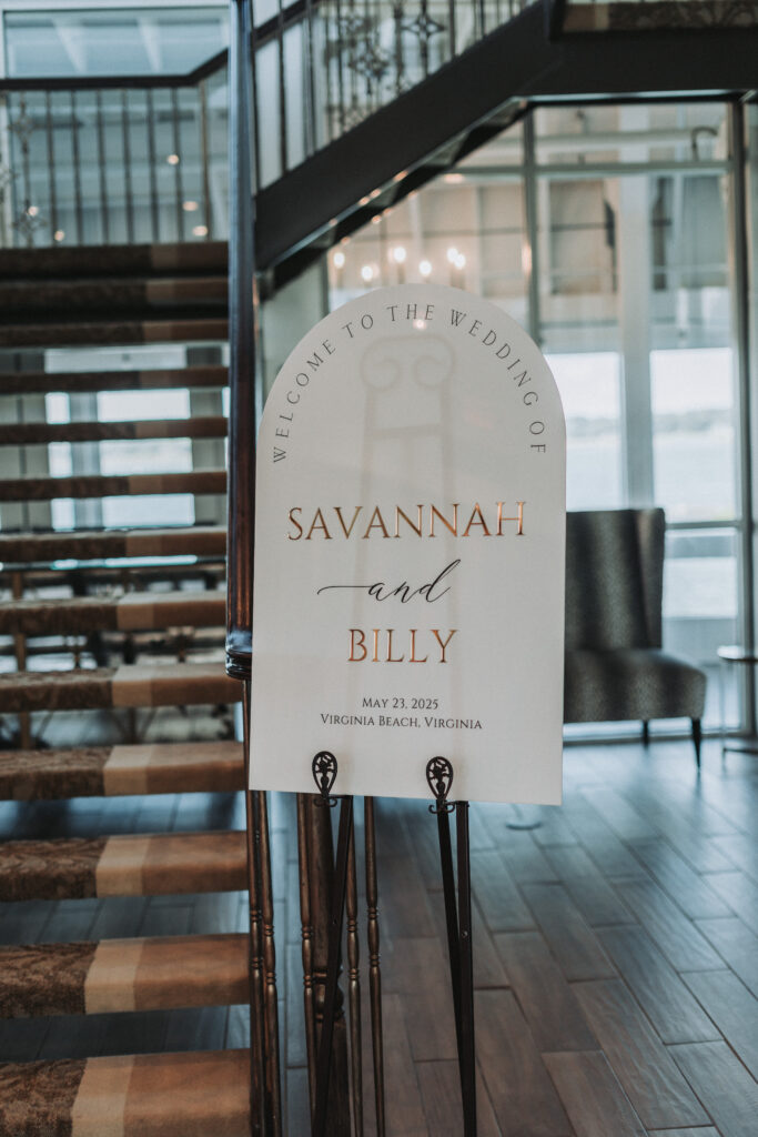 Elegant white welcome sign with gold and black lettering for Savannah and Billy’s wedding at the Lesner Inn in Virginia Beach, captured by Quinn Photography LLC.