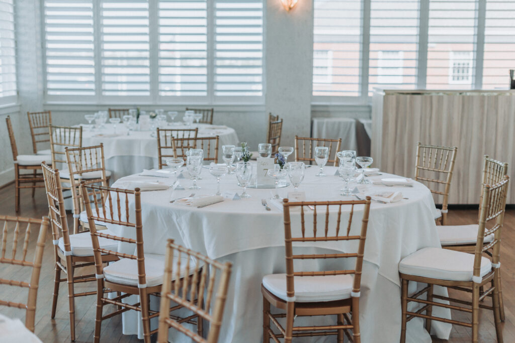 Reception tables with white linens, gold chiavari chairs, and glassware at the Lesner Inn.