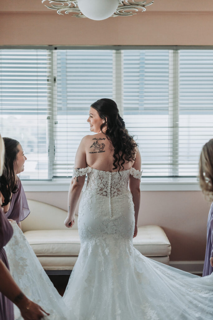 Bride smiles while bridesmaids adjust her train during getting ready at Lesner Inn — captured by Quinn Photography LLC.