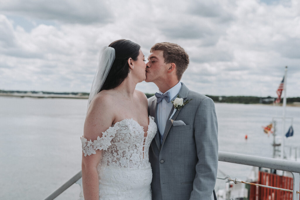 Bride and groom sharing a kiss with the American flag in the background at Lesner Inn