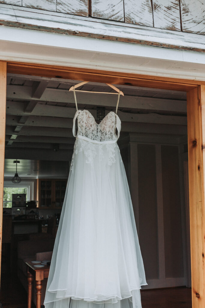 Lace and tulle wedding dress at Due Sorelle, hanging inside rustic doorway. Captured by Virginia wedding photographer Quinn Photography LLC.