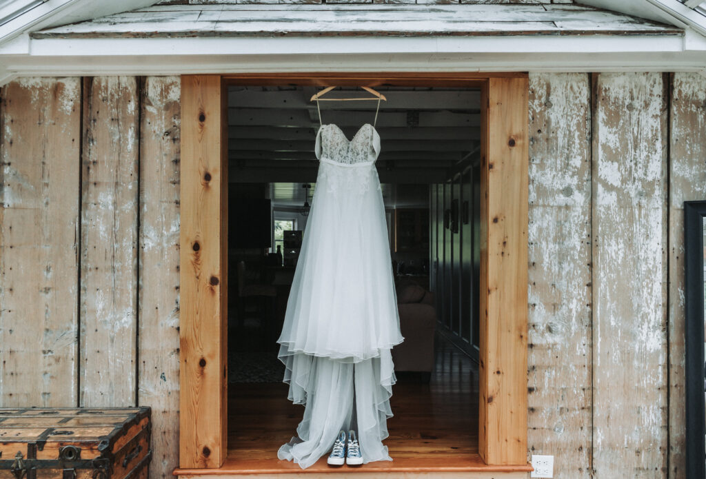 Full-length wedding dress hanging in rustic doorway with weathered wood at Due Sorelle. True-to-color photo by Quinn Photography LLC.