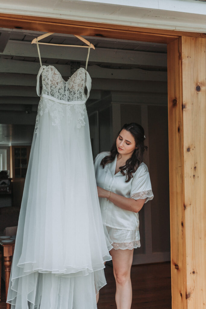 Bride admires her wedding dress hanging in a wooden doorway at Due Sorelle.