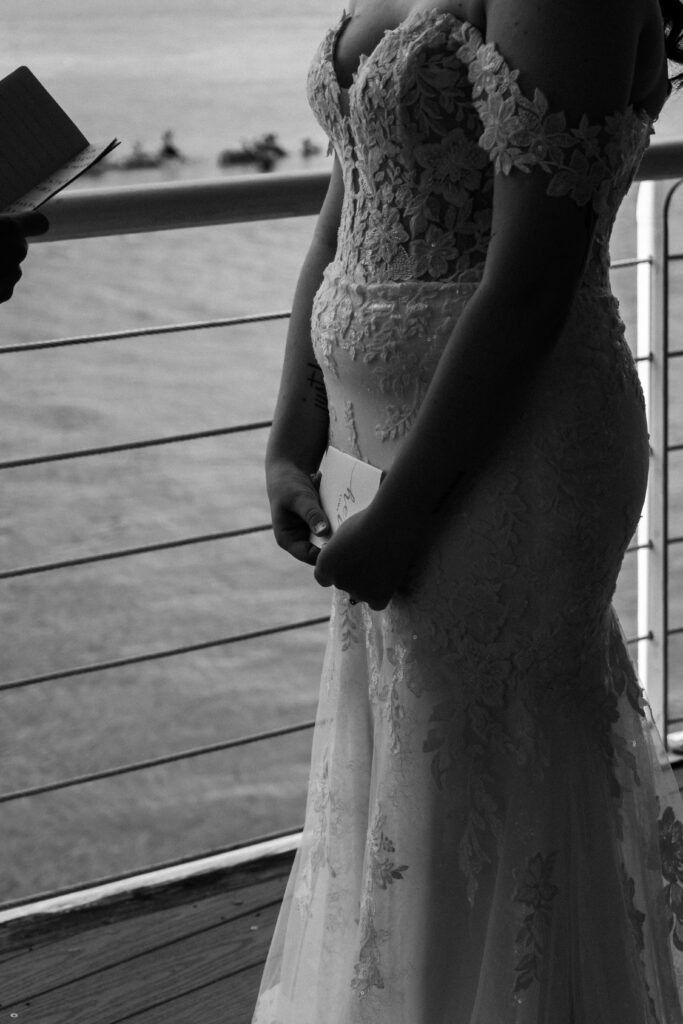 Close-up of the bride in a lace gown holding her vow book during the ceremony at Lesner Inn.
