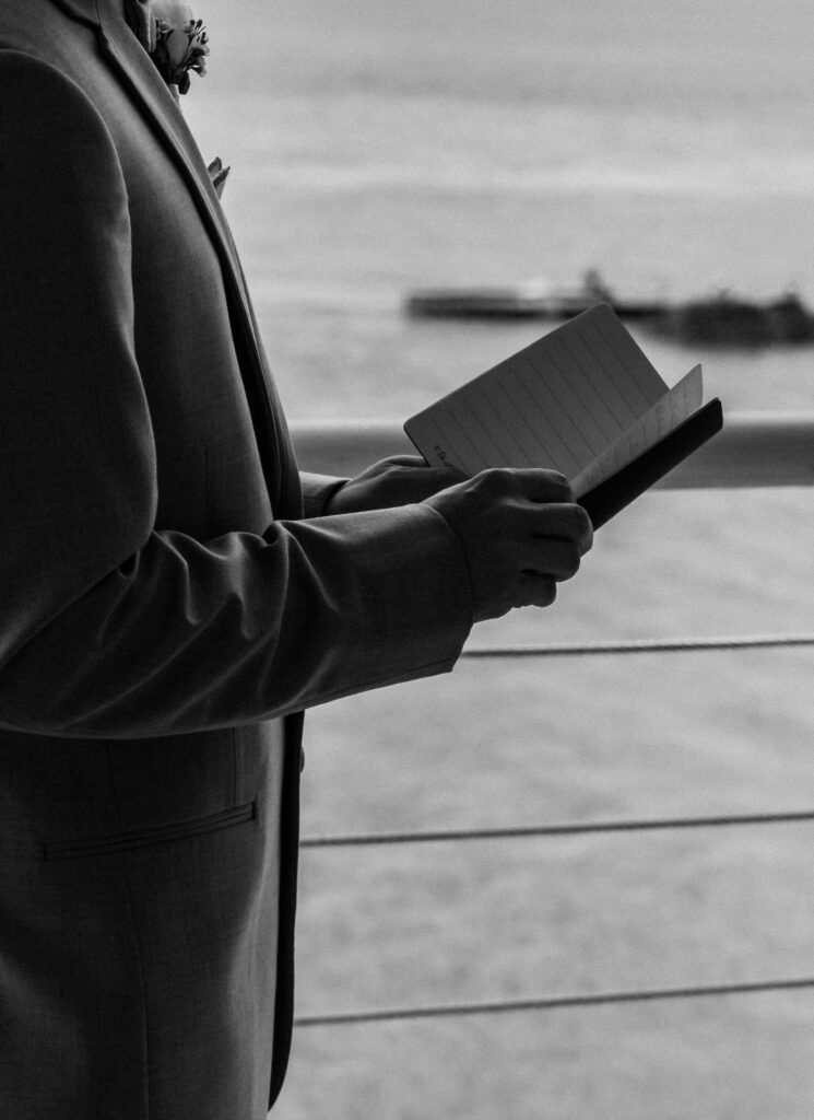 Groom holding open vow book during the wedding ceremony at Lesner Inn in Virginia Beach.