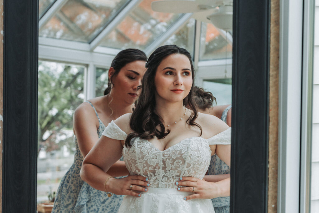 Bride gets help into her gown in front of a mirror at Due Sorelle.