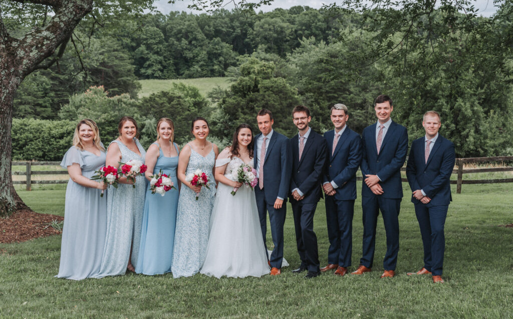 Wedding party smiling under a tree in blue and blush tones at Due Sorelle in Ruckersville, VA