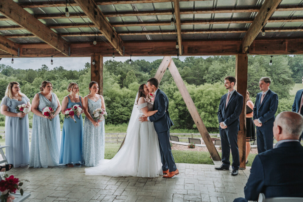 Bride and groom share their first kiss under the wooden pavilion at Due Sorelle in Ruckersville