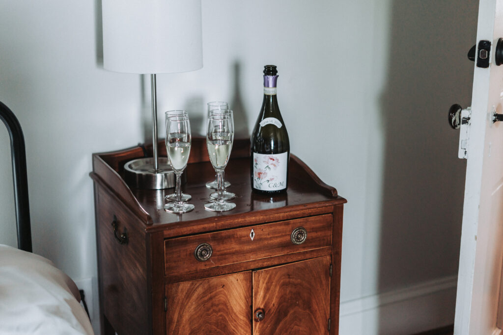 Custom-labeled champagne bottle with wedding date and initials beside glasses on a nightstand at Due Sorelle