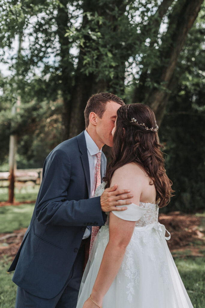 Groom kisses bride's forehead during a private moment beneath the trees at Due Sorelle in Ruckersville, VA.