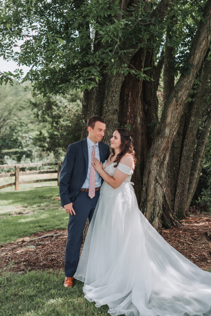 Bride and groom leaning against a tree, gazing into each other’s eyes on their wedding day at Due Sorelle.